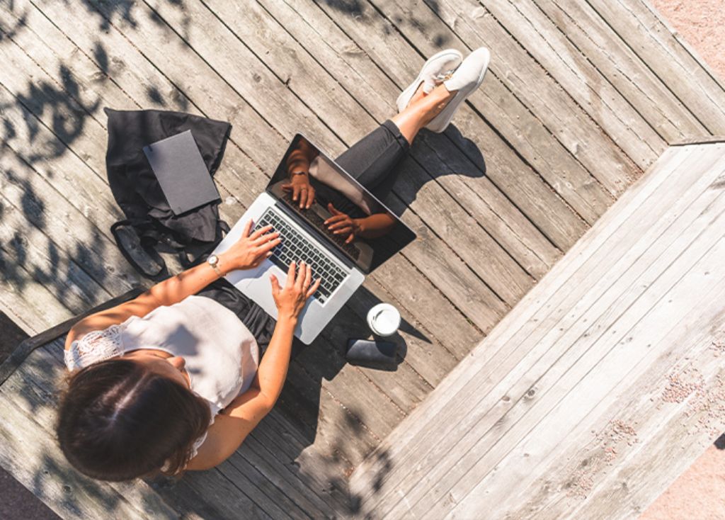 Info Teaser - Frau arbeitet draussen am Laptop